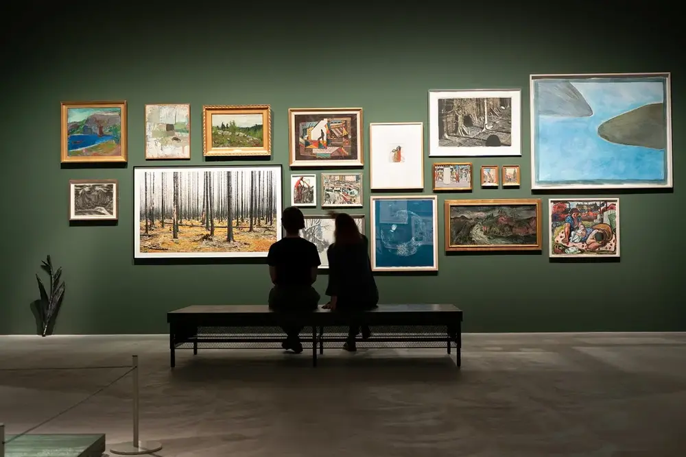 Två personer studerar tavlor på väggen på konstmuseet